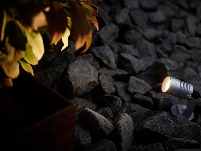 Spotlight Garden från Hide-a-lite lyser upp buske i trädgård.